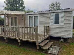 a mobile home with a large wooden deck at Mobil-Home/Bungalow in Le Perrier