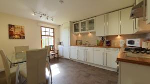 a kitchen with white cabinets and a table and chairs at Roseford Apartment in Crail