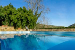 a swimming pool with blue water and trees in the background at DordogneView in Calès
