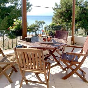 a wooden table and chairs on a balcony with the ocean at Naiada Apartments Milina in Milína