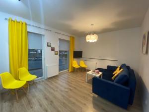 a living room with a blue couch and yellow chairs at Apartament Karpacz 2- pokojowy in Karpacz