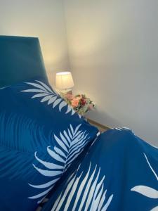 a bed with a blue comforter with a lamp and flowers at Apartament Karpacz 2- pokojowy in Karpacz