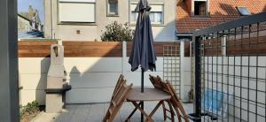 una mesa con sombrilla y 2 sillas en el balcón en GRAINES AU VENT, en Berck-sur-Mer