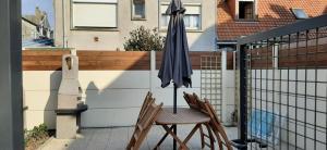 d'une table avec un parasol et deux chaises sur le balcon. dans l'établissement GRAINES AU VENT, à Berck-sur-Mer