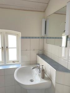 een witte badkamer met een wastafel en een spiegel bij Pension Walfischhaus in Born