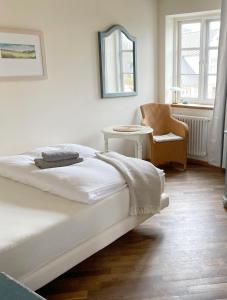 a white bedroom with a bed and a chair at Pension Walfischhaus in Born