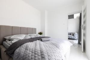 ein Schlafzimmer mit einem Bett mit einer grauen Bettdecke und einem Spiegel in der Unterkunft Apartament z basenem i kominkiem ,,baltic sun” in Sztutowo