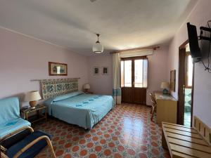 a bedroom with a bed and a chair in it at Hotel L'Oasi in Cala Gonone