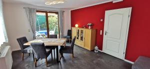 ein Esszimmer mit roten Wänden sowie einem Tisch und Stühlen in der Unterkunft Ferienhaus Heidegeist in Soltau