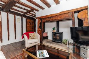ein Wohnzimmer mit einem TV und einem Kamin in der Unterkunft 1400 Cottage An enchanting unique stay in Henley on Thames