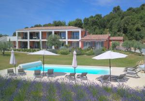 a pool with chairs and umbrellas in front of a house at Le Mas des Oliviers in Gréoux-les-Bains