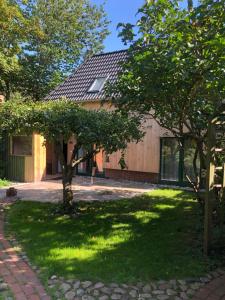 een huis met een tuin met bomen ervoor bij Ferienhaus Peerhus in Katingsiel
