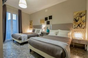 a hotel room with two beds and a window at Musica Guest House in Alghero