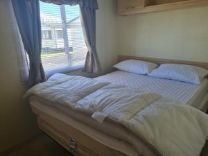 a bed in a bedroom with a window at 8 Berth Coral Beach (Mirage Super) in Ingoldmells