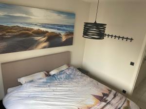 a bedroom with a bed and a painting on the wall at Trendy & ruim appartement centum Oostende in Ostend