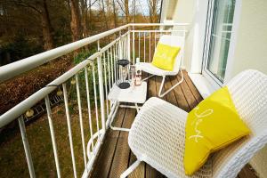 a balcony with two chairs and a lamp on it at FLEESENTRAUM Seevilla Kormoran - Direkt am Fleesensee - Familien und Aktivurlauber - Whirlpool Sauna Garten Nintendo - SUP Kanu Kajak inklusive in Göhren-Lebbin