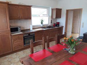 a kitchen with wooden cabinets and a table with flowers on it at Ferienwohnung Kleeblatt in Alpen
