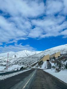 an empty road with snow covered mountains in the background at Apartamento en estación de esquí y montaña alto campoo in Brañavieja