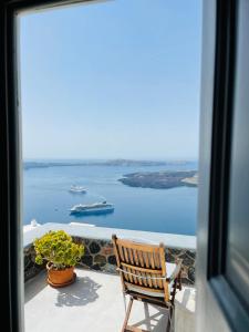 a wooden chair sitting on a balcony looking out at the water at Ikia Kriton in Imerovigli