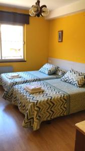 2 camas en una habitación con paredes amarillas en Pensión Casa Corro en Carreña de Cabrales 