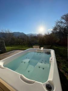 a jacuzzi tub in a yard with the sun in the background at "Le Cottage" Appartements avec SPA privatif in Saint-Bonnet-en-Champsaur