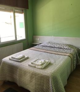 a green bedroom with a bed with two towels on it at Pensión Casa Corro in Carreña de Cabrales 