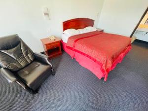 1 dormitorio con cama, silla y escritorio en Executive Inn, en Muskogee