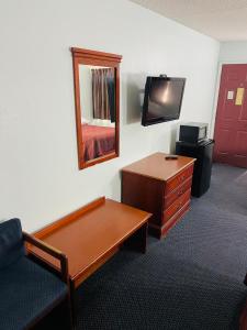 Habitación con escritorio, TV y silla. en Executive Inn, en Muskogee