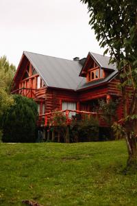 a log cabin with a porch in the grass at La Campiña in San Carlos de Bariloche +12 photos