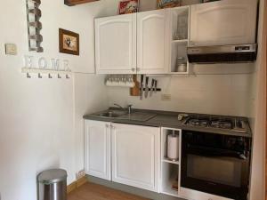 uma cozinha com armários brancos e um forno com placa de fogão em Appartamento ad Ovindoli em Ovindoli