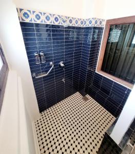 uma casa de banho com um chuveiro com paredes em azulejos azuis em East Indies Mansion em George Town