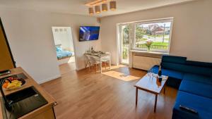 a living room with a blue couch and a table at Słoneczna Przystań - Apartament in Szczedrzyk