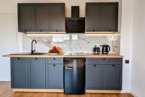 a kitchen with blue cabinets and a black refrigerator at Słoneczna Przystań - Apartament in Szczedrzyk