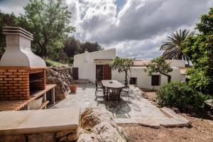 a patio with a table and chairs in front of a house at Casa rural Can Rotes con jardin y barbacoa in Sant Joan de Labritja
