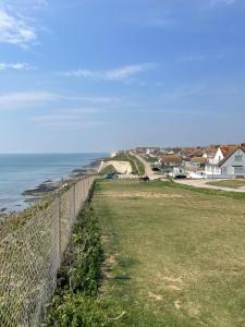 a fence next to the ocean and a beach at Poolside in Peacehaven