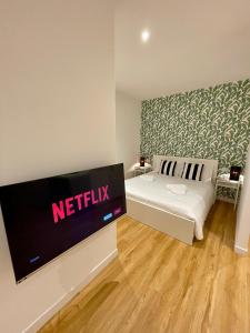 Vento Suites في كالياري: غرفة نوم مع سرير مع علامة نتفلكس على الحائط