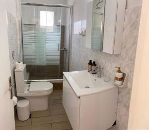 a white bathroom with a toilet and a sink at Villa Loukia in Corfu