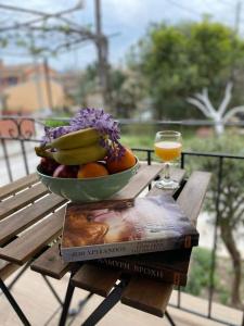 un bol de fruta en una mesa con un libro y un vaso de zumo en Villa Loukia, en Corfú