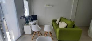 a living room with a green chair and two white stools at La casa de la luz in Santander