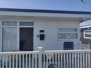 a white house with a porch and a door at L&L's Lodge, A small but perfectly formed chalet in Chapel Saint Leonards