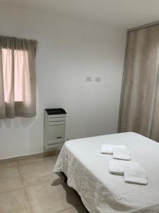 a white bedroom with a bed with towels on it at Depto por día Santa Rosa in Santa Rosa