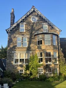 an old stone house with a clock on top at Wheatlands Lodge Guesthouse - Adults Only - Free car park - Licensed Venue in Windermere