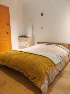 a bedroom with a bed with a yellow blanket on it at Chambre chez l habitante "Lys des incas" in Derval