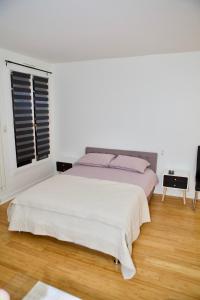 um quarto branco com uma cama e uma janela em STUDIO JASMIN em Paris