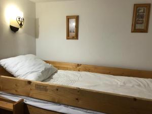 Le Chamois des Alpages de Reberty ski au pied في ليه مينوير: غرفة نوم بسرير خشبي مع شراشف بيضاء