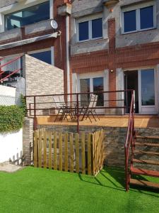 ein Haus mit einer Terrasse mit einem Zaun und Gras in der Unterkunft La casa de Gonso in Mogro