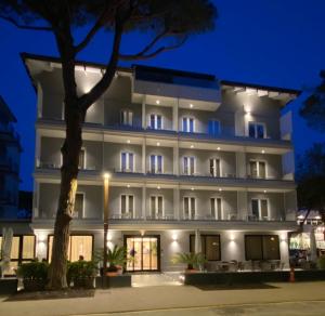 een groot wit gebouw met een boom ervoor bij Hotel Balaton in Riccione