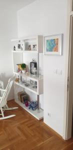 a white book shelf in a room with a chair at Apartman Aura in Zagreb