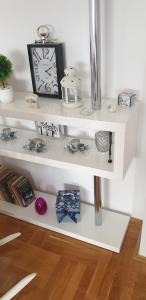 a white shelf with a clock and other items on it at Apartman Aura in Zagreb