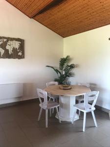 a dining room table with white chairs and a potted plant at les gîtes de La Cossais in Saint-Cyr-en-Talmondais